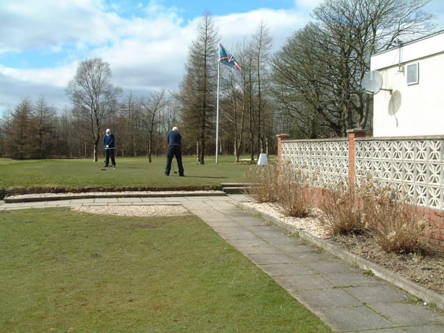 Golfers on the practice green beside the clubhouse at Shotts