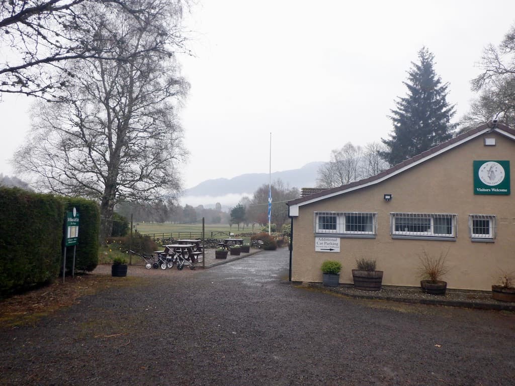 The clubhouse at St Fillans on a misty morning, the course beyond the picnic tables