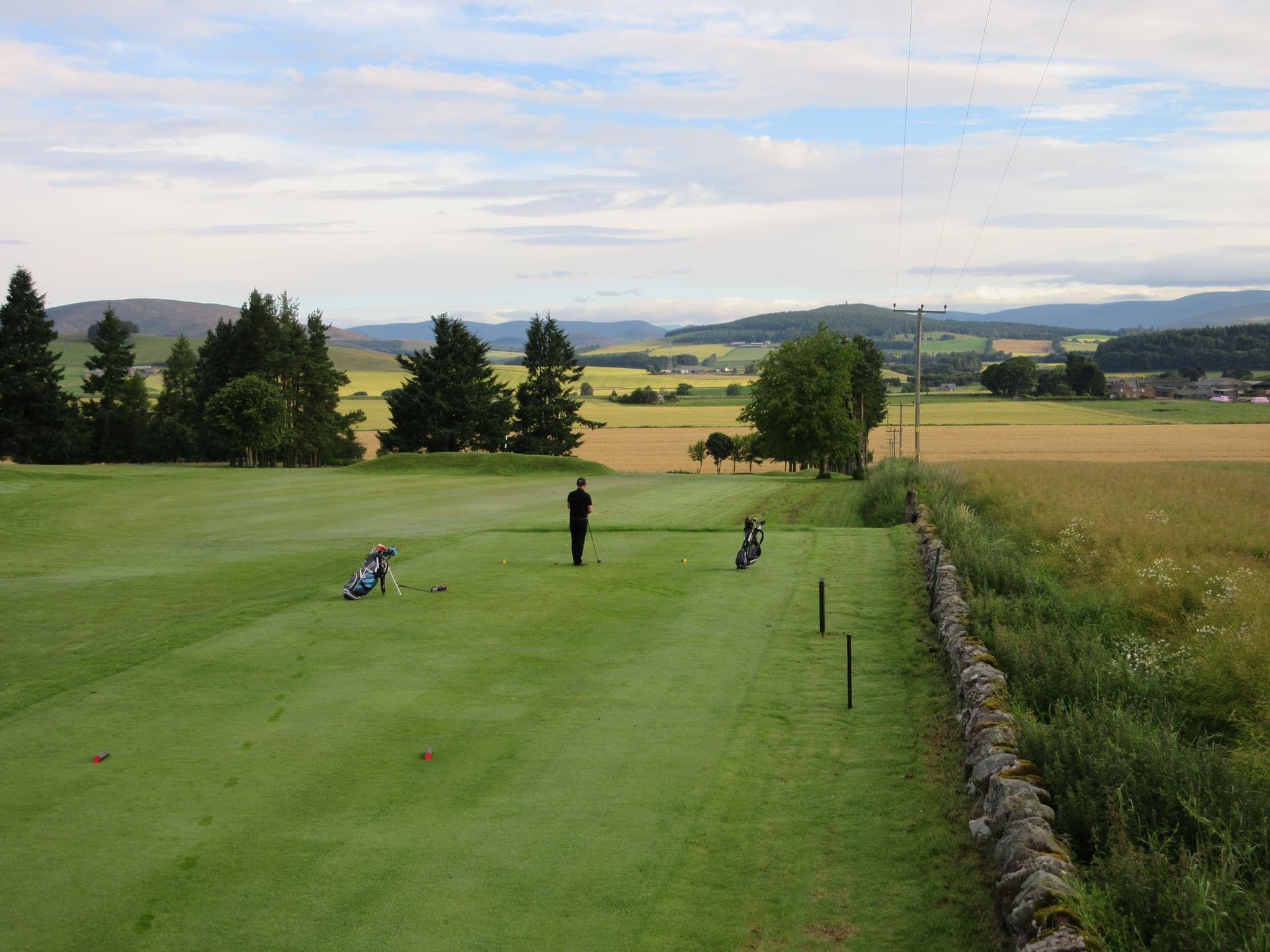 A golfer on the tee at Kirriemuir, the Angus glens on the skyline
